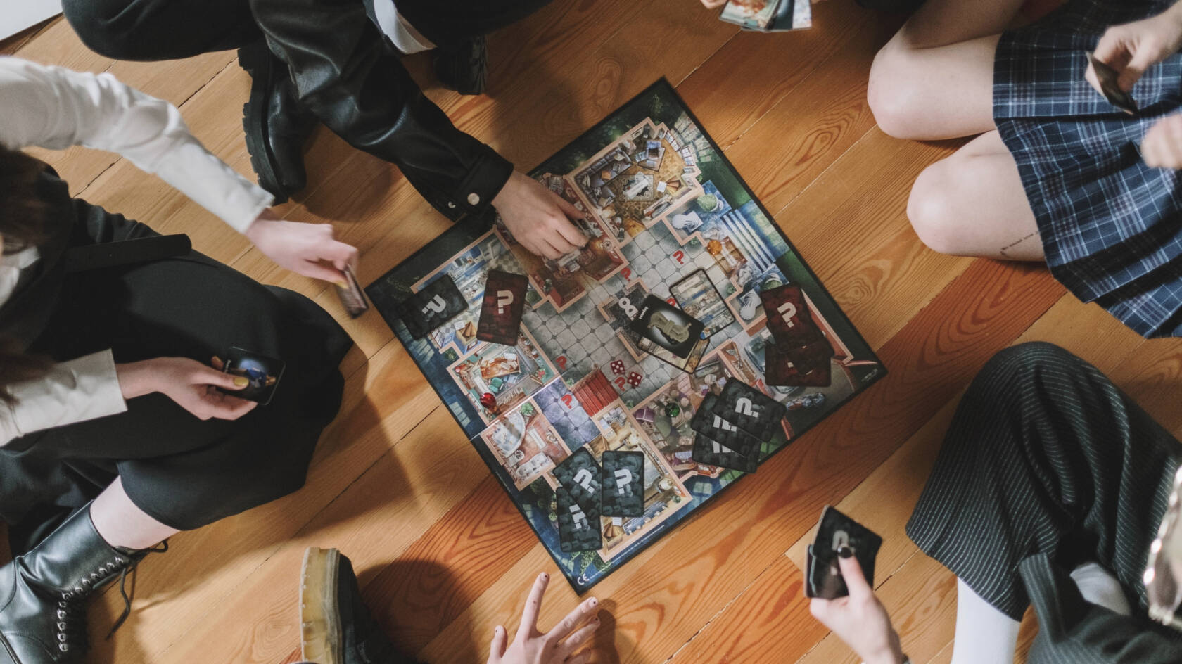 Människor sitter på golvet runt ett bordspel och spelar.
