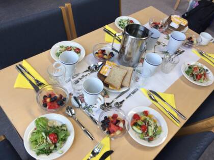 Pöytään katettu ruokailuvälineet, salaatit ja lautasliinat viidelle hengelle. Kirkkoravintola Voimala.