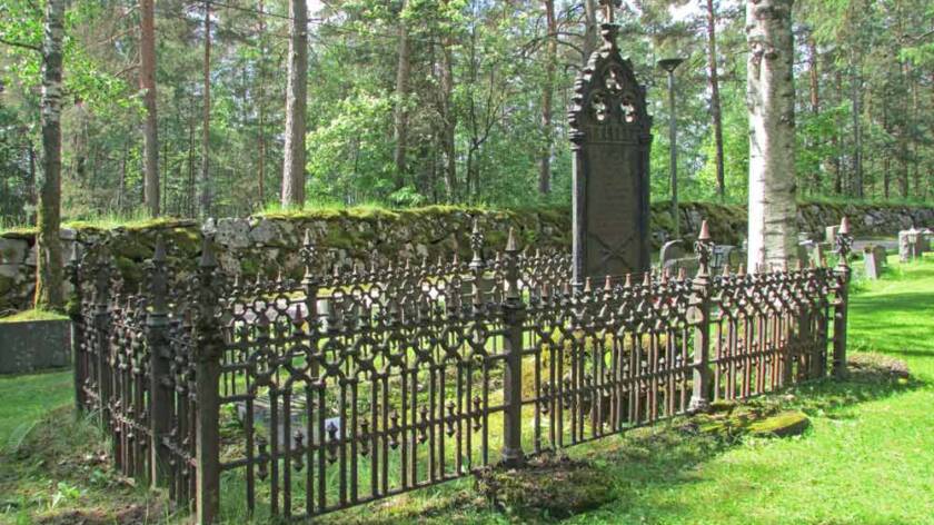 Vanha hautamuistomerkki, jonka ympärillä takorautainen koristeellinen aita.