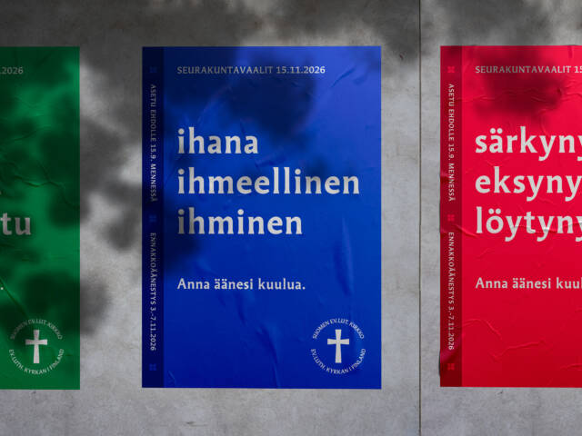 Alikulkutunnelin seinällä sininen vaalimainos. Ihmisiä kulkee ohi.