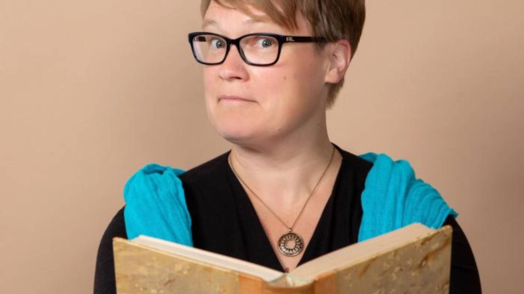 Suomen ja Pohjoismaiden historian professori Anu Lahtinen vanha kirja kädessään.