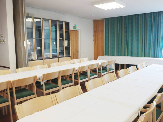 Kivistön kirkon seurakuntasali. Kaksi pitkää pöytää ja tuoleja.