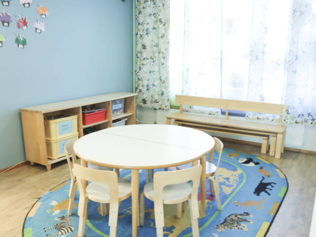 Kaivosristin kerhotilan huone jossa lasten pyöreä pöytä, tuolit, pitkä penkki ja leluhylly.