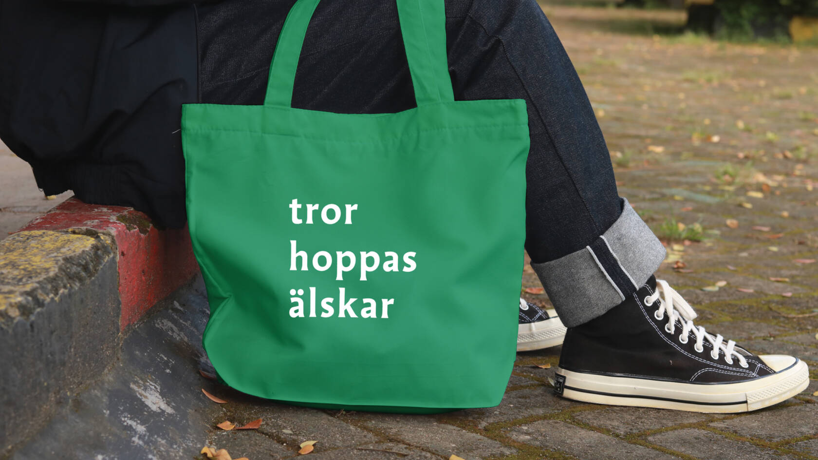 Person som sitter med tygkasse med texten "tror hoppas älskar".