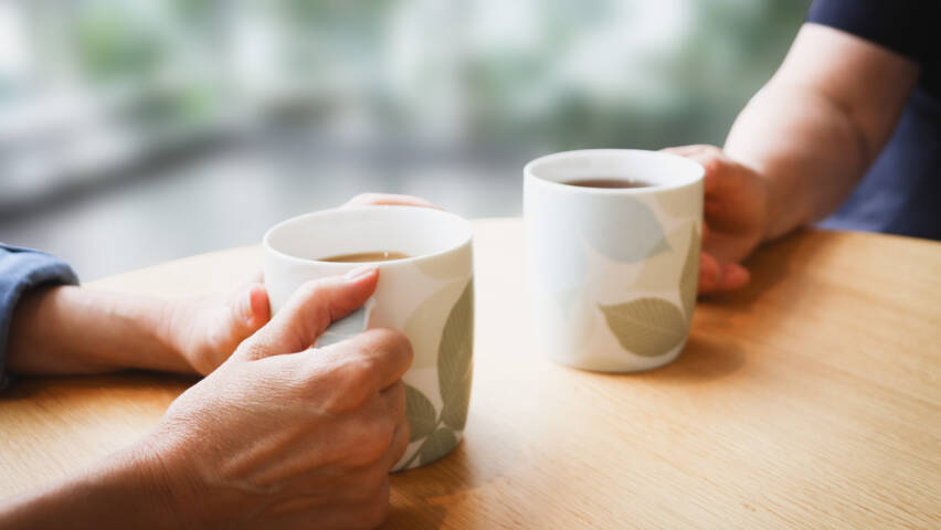 kaksi kahvikuppia, joita kädet pitelevät