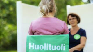 Tuolissa istuva juttelee toisen kuuntelijan kanssa.