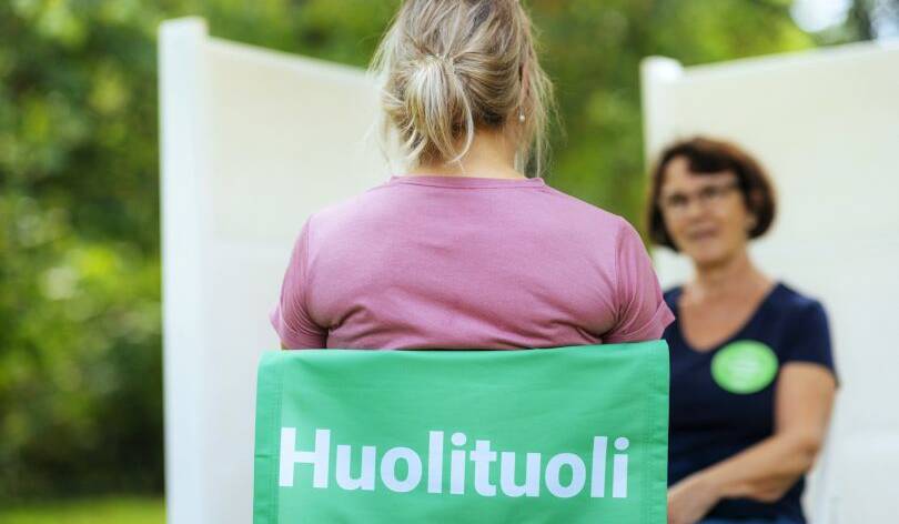 Tuolissa istuva juttelee toisen kuuntelijan kanssa.